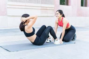 Çekici genç bir kadın gülümsüyor ve şehirde yürüyüş yaparken arkadaşına bakıyor.