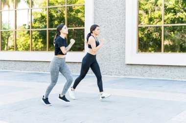 Yaya yolunda koşarak ilerleyen kararlı genç bayan arkadaşlarla dolu.