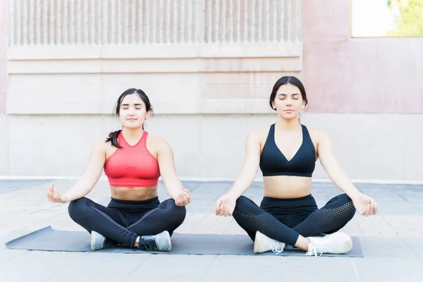 Mujeres Hermosas Practicando Yoga Mientras Sientan Estera Contra Pared Ciudad —  Fotos de Stock