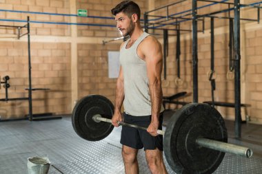 Kendine güvenen İspanyol sporcu ağırlık kaldırırken spor kulübüne bakıyor.