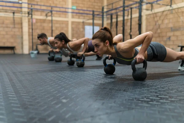 Dedikerade Kvinnor Och Manliga Idrottare Gör Armhävningar Kettlebells Gymmet Träningen — Stockfoto