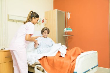 Hemşire, hastanede yataktan kalkmak için kıdemli hastaya yardım ediyor.