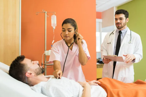 Ärztin Untersucht Kranke Patientin Mit Stethoskop Während Männlicher Arzt Berichte — Stockfoto