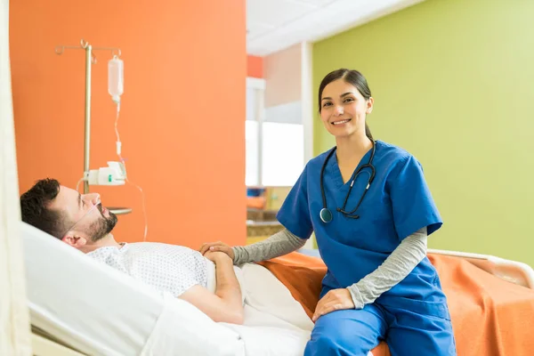 Glimlachende Jonge Verpleegster Troosten Mannelijke Patiënt Terwijl Zitten Bed Het — Stockfoto