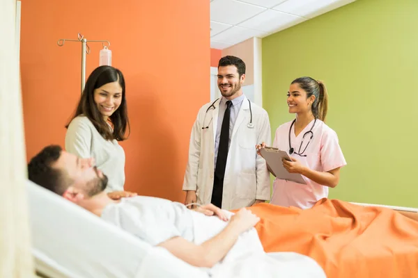 Χαμογελώντας Γιατροί Κοιτάζοντας Αρσενικό Ασθενή Γυναίκα Ενώ Στέκεται Από Άρρωστο — Φωτογραφία Αρχείου