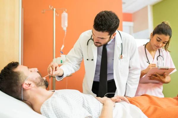 Männlicher Arzt Kontrolliert Kehle Einer Patientin Während Weibliches Gesundheitspersonal Berichte — Stockfoto