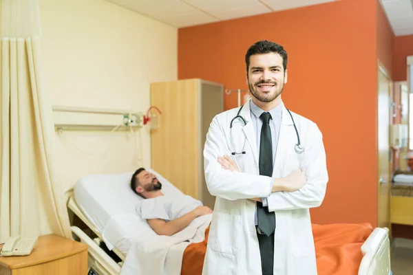 在医院病床上与病人交叉着双臂微笑的拉美裔医护人员 — 图库照片