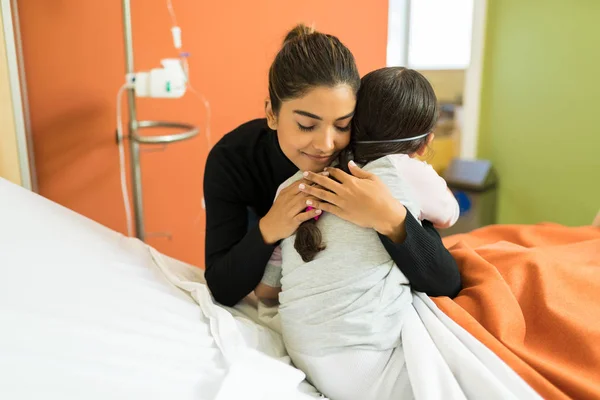 Νεαρή Γυναίκα Αγκαλιάζει Την Άρρωστη Κόρη Της Στο Κρεβάτι Του — Φωτογραφία Αρχείου