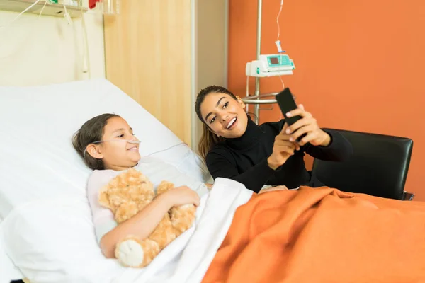 Madre Sonriente Mostrando Smartphone Hija Durante Tratamiento Hospital — Foto de Stock