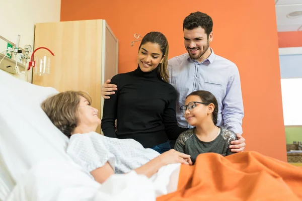 Smiling Family Visiting Senior Woman Treatment Hospital — Stock Photo, Image