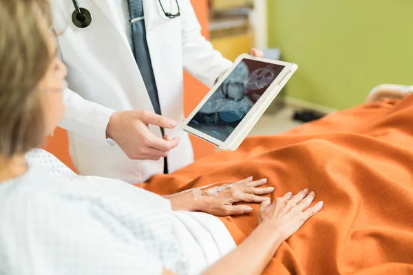 中段医生在医院向老年病人展示数码平板电脑的X光报告 — 图库照片