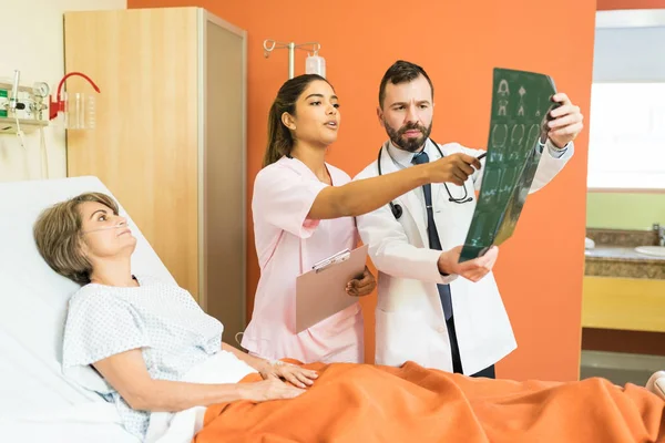 Latijnse Artsen Bespreken Röntgendiagnose Terwijl Senior Patiënt Bed Ligt Het — Stockfoto