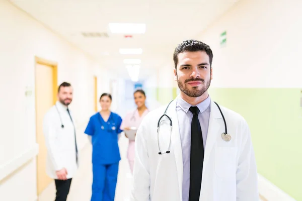 Hispanic Stilig Läkare Står Vid Väggen Med Medarbetare Bakgrunden Sjukhuset — Stockfoto