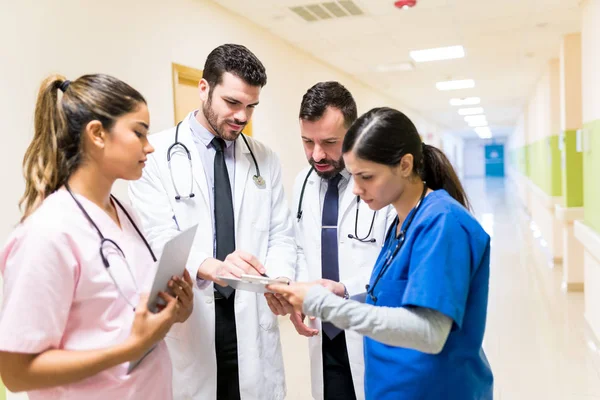 Ärzte Und Krankenschwestern Betrachten Medizinische Berichte Während Sie Krankenhausflur Diskutieren — Stockfoto