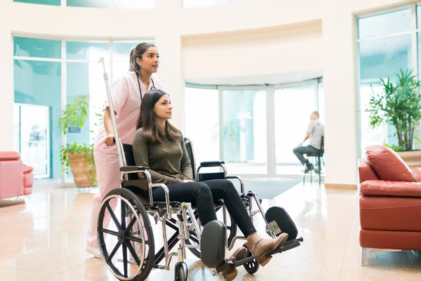 Young Orderly Pushing Discharged Woman Wheelchair Lobby Hospital — Stock Photo, Image