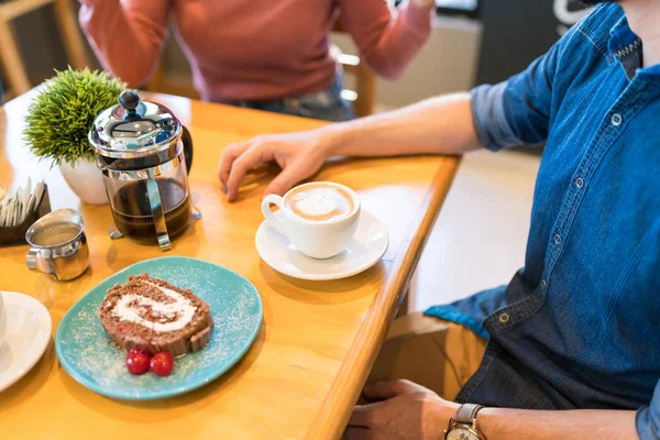 カフェのテーブルで友人とコーヒーとデザートを持っている男の真ん中のセクション — ストック写真