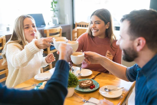 Amigos Masculinos Femeninos Brindando Por Tazas Café Mientras Están Sentados —  Fotos de Stock