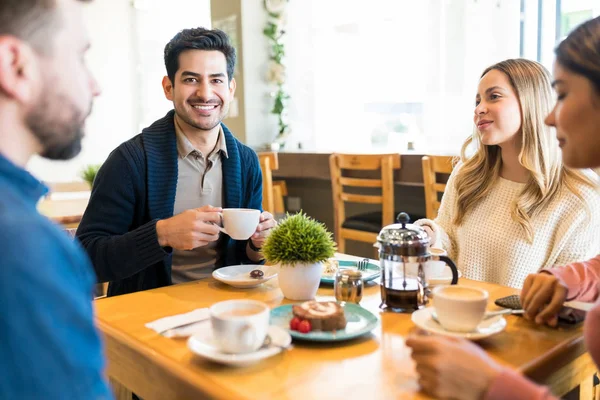 Young man having coffee with friends while spending leisure time at cafe