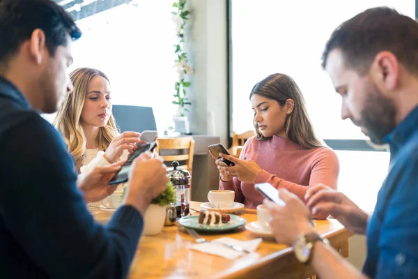 Amigos Masculinos Femininos Distraídos Usando Smartphones Enquanto Sentados Juntos Restaurante — Fotografia de Stock