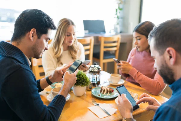 Amigos Masculinos Femininos Distraindo Com Smartphones Enquanto Sentados Juntos Café — Fotografia de Stock