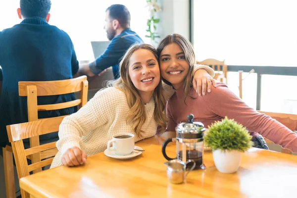 Sonrientes Amigas Jóvenes Disfrutando Del Café Mientras Sientan Con Los —  Fotos de Stock