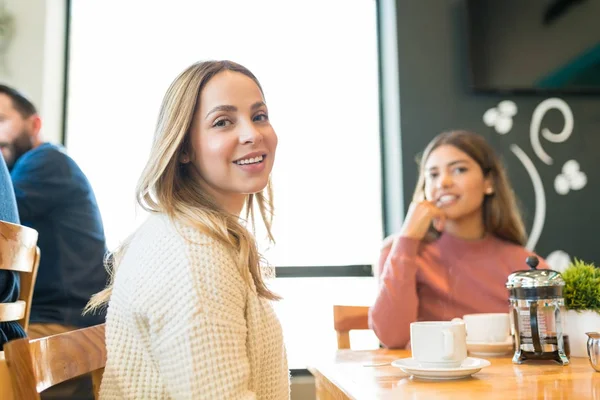 レストランのテーブルでコーヒーを飲みながら友人と座っている美しい女性の肖像画 — ストック写真