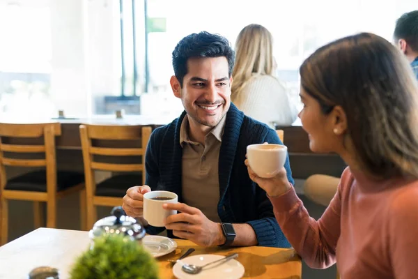 Uśmiechnięty Młody Człowiek Patrząc Dziewczynę Podczas Picia Kawy Przy Stole — Zdjęcie stockowe