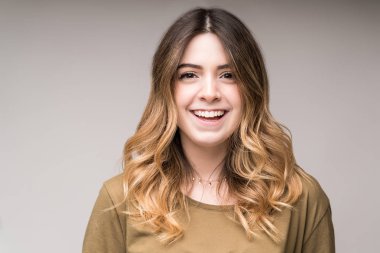 Gri arka planda neşeli, genç bir bayanın yakın çekimi.