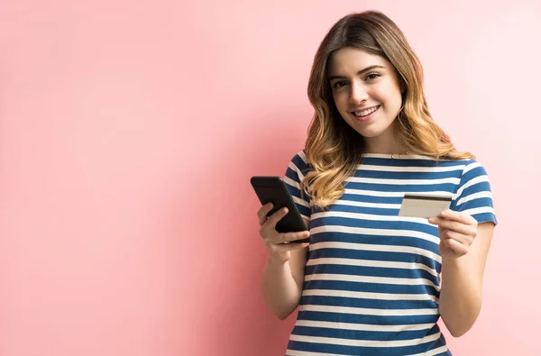 Glad Attraktiv Ung Kvinna Innehav Kreditkort Och Mobiltelefon Mot Korall — Stockfoto