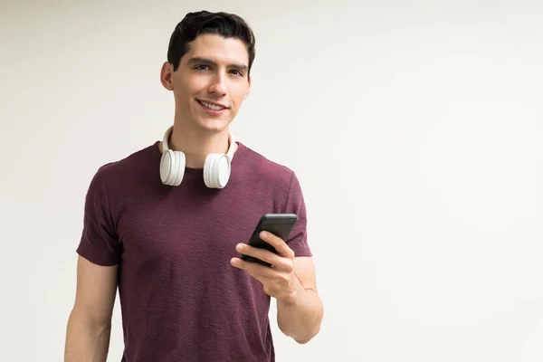 Sorrindo Bonito Homem Caucasiano Com Fones Ouvido Segurando Smartphone Enquanto — Fotografia de Stock