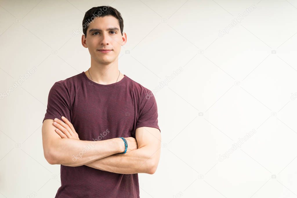 Confident handsome young male standing with arms crossed against white background