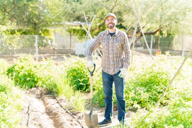 Gülümseyen orta yaşlı çiftçi yaz boyunca çiftlikte kürekle dikiliyor.