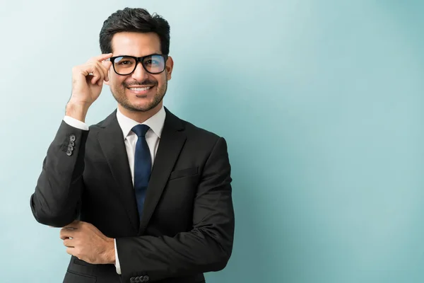 Handsome Hispanic Businessman Touching Eyeglasses While Smiling Blue Background — Stock Photo, Image