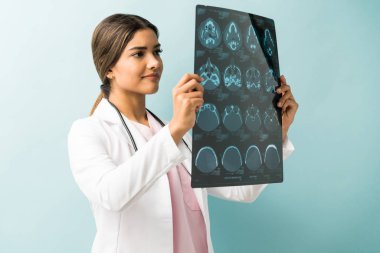 Stüdyoda dikilirken röntgeni inceleyen güzel kadın doktor.