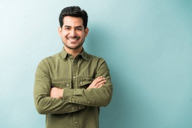 Happy attractive man standing with arms crossed against colored background