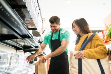Kendine güvenen satıcı markette kadınlar için yiyecek paketliyor.