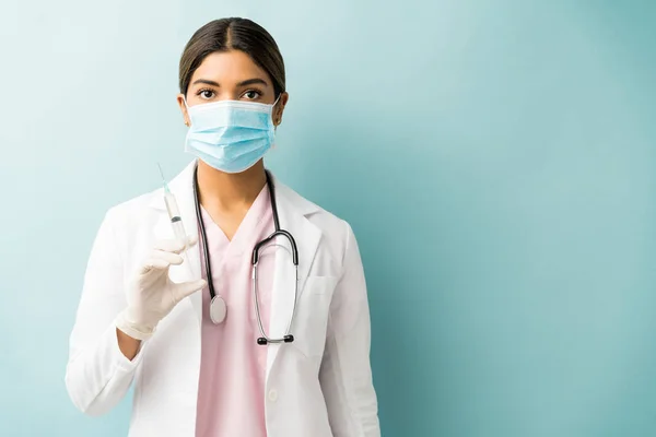 Hispanic Young Doctor Holding Syringe While Wearing Mask Blue Background — Stock Photo, Image