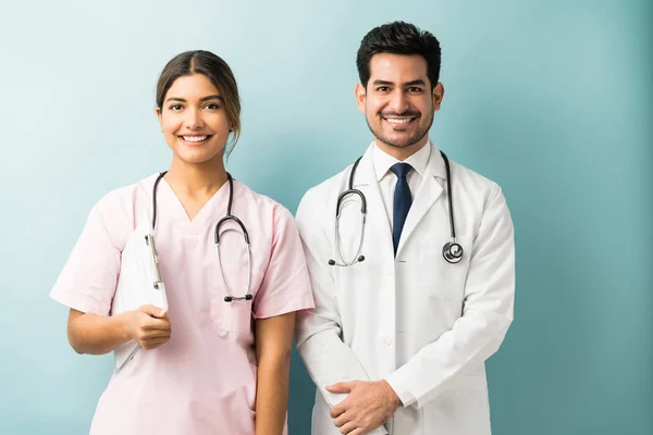 穿着制服站在蓝色背景下的西班牙裔医务工作者面带微笑 — 图库照片