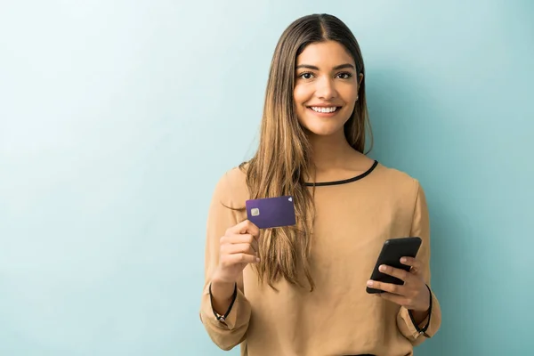 Mulher Latina Sorrindo Segurando Cartão Crédito Smartphone Enquanto Está Contra — Fotografia de Stock