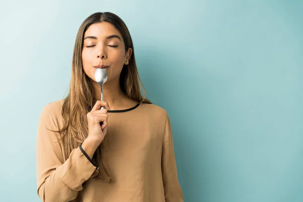 Latino Jonge Vrouw Proeven Lepel Terwijl Staande Blauwe Achtergrond — Stockfoto