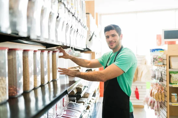 Confident Hispanic Male Owner Arranging Food Containers Shelf Grocery Store — Stock Photo, Image