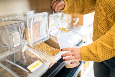 Kadının orta kısmı markette şekerleri kabın içine koyuyor.