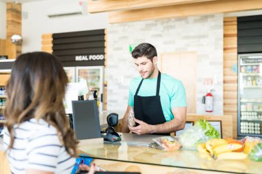 Handsome male owner scanning products at checkout counter in supermarket