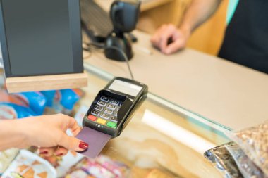 Bakkalda kredi kartıyla ödeme yapan bir kadının görüntüsü.