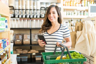 Markette akıllı telefon kullanırken gülümseyen kadın portresi