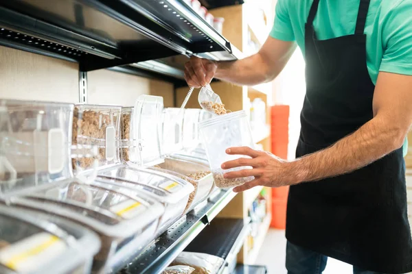 ラテン系の男性の所有者の中央部は食料品店で容器に食品を入れて — ストック写真