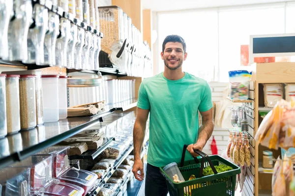 Jovem Latino Feliz Carregando Cesta Enquanto Faz Compras Mercearia — Fotografia de Stock
