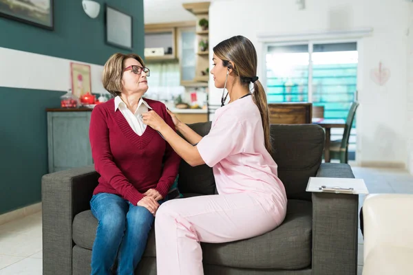 Mulher Cuidadora Examinando Idosa Sentada Sofá Casa — Fotografia de Stock