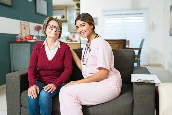 Portrait Confident Female Nurse Sitting Senior Woman Sofa Home — Stock Photo, Image