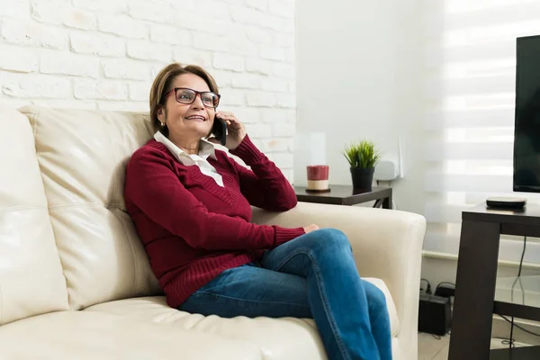 Sorrindo Mulher Sênior Falando Smartphone Enquanto Sentado Sofá Casa — Fotografia de Stock